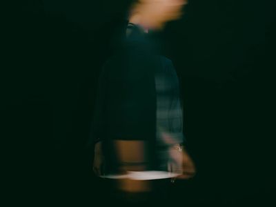Abstract motion blur of a person stretching in a dark room.