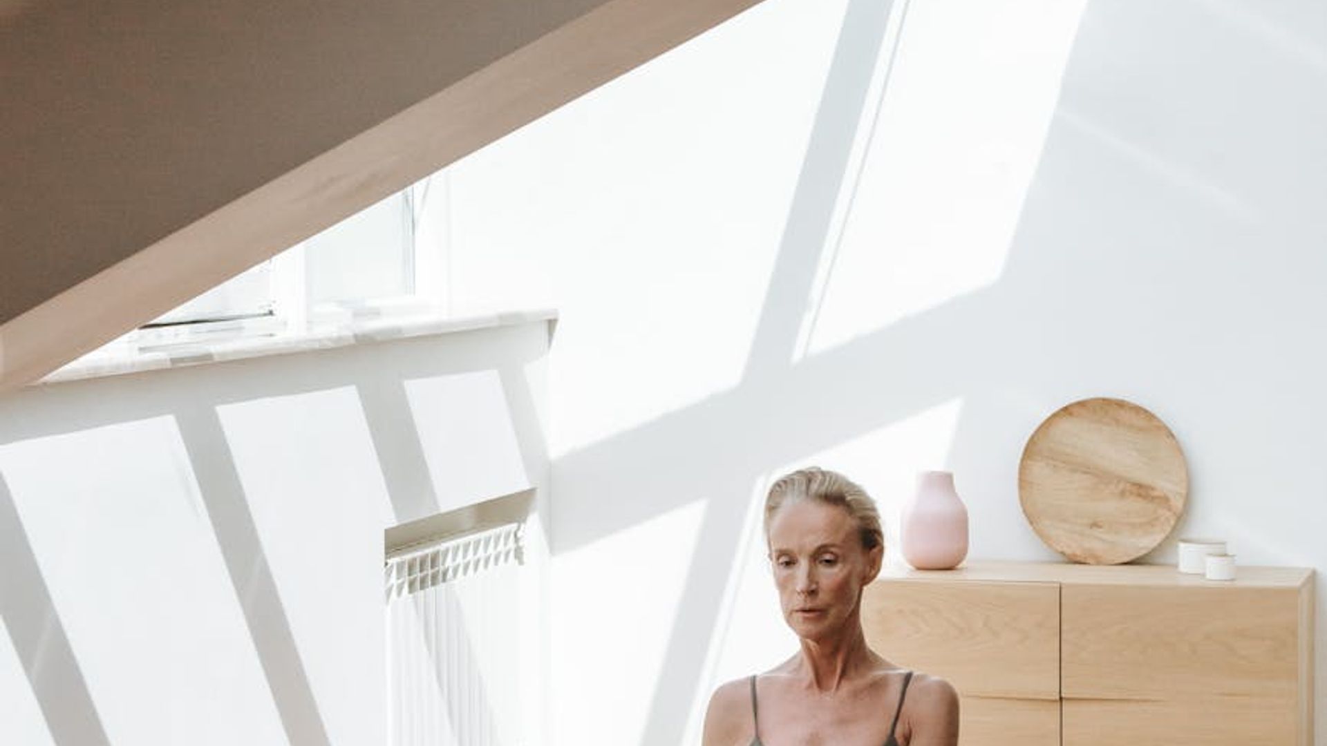 Person practicing yoga in a bright minimalistic studio room.